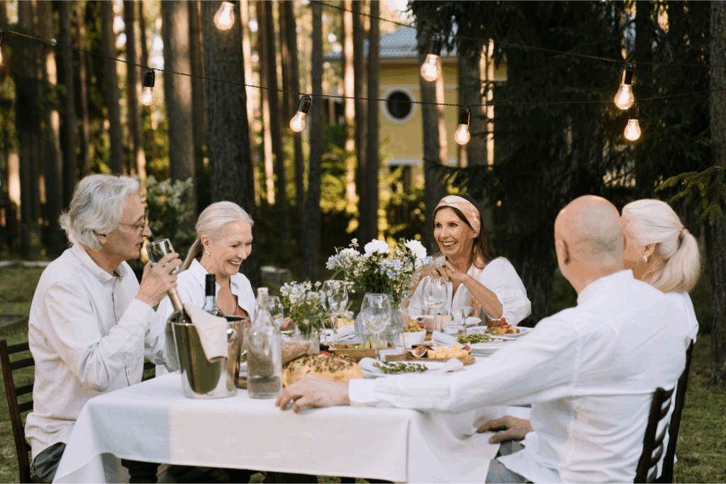 Group of retirees gathering outdoors for a social dinner, highlighting the importance of maintaining friendships and social connections to prevent divorce in retirement.